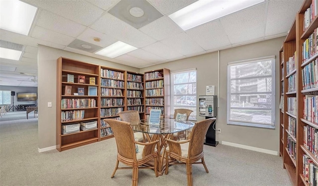 interior space with a paneled ceiling, light colored carpet, and a healthy amount of sunlight