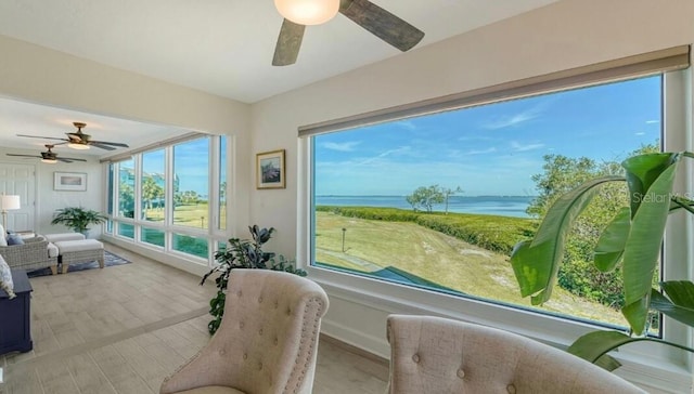 sunroom / solarium featuring a water view and ceiling fan