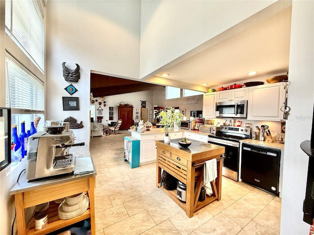 kitchen with a high ceiling, white cabinetry, and appliances with stainless steel finishes