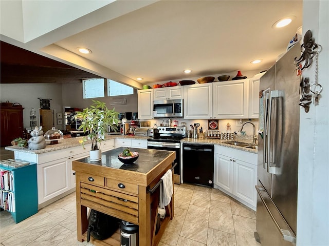 kitchen featuring appliances with stainless steel finishes, sink, white cabinetry, and a center island