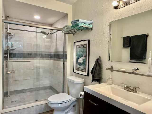 bathroom featuring toilet, a shower with door, and vanity