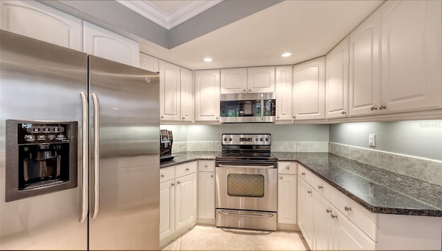 kitchen with appliances with stainless steel finishes, dark stone counters, white cabinetry, and ornamental molding