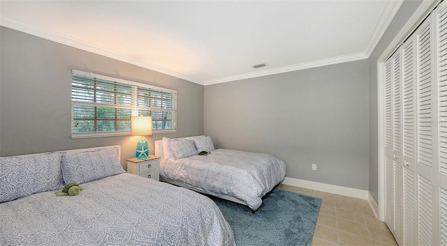 bedroom with light tile patterned floors, a closet, and crown molding