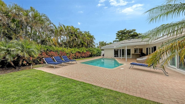 view of swimming pool with ceiling fan, a patio area, and a yard