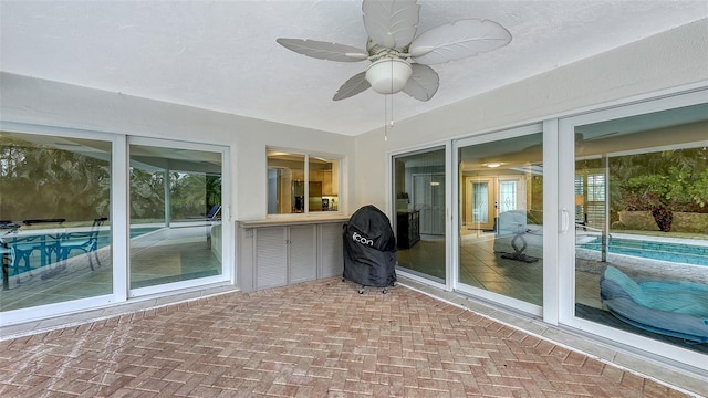 unfurnished sunroom with ceiling fan