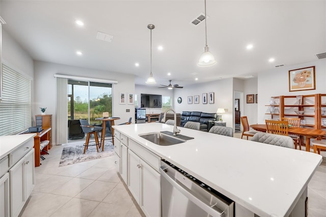 kitchen with stainless steel dishwasher, hanging light fixtures, sink, white cabinetry, and a kitchen island with sink