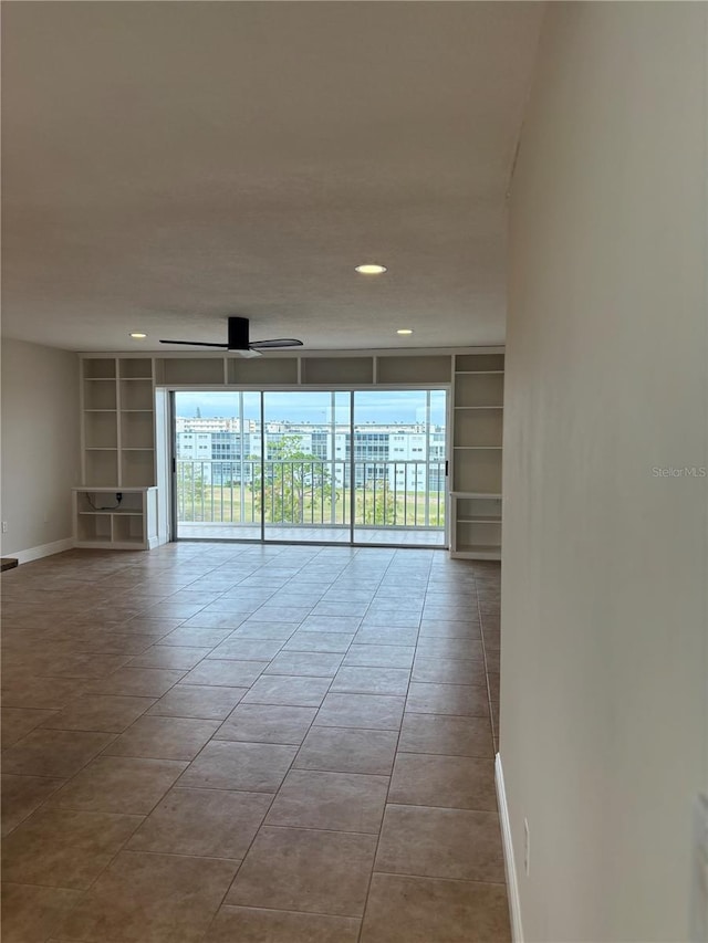 empty room with ceiling fan, plenty of natural light, built in shelves, and floor to ceiling windows