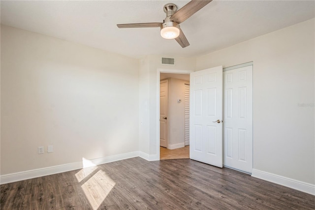 unfurnished bedroom with dark hardwood / wood-style flooring, a closet, and ceiling fan