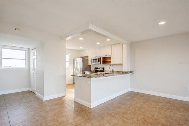 kitchen with sink, appliances with stainless steel finishes, kitchen peninsula, light stone countertops, and white cabinets