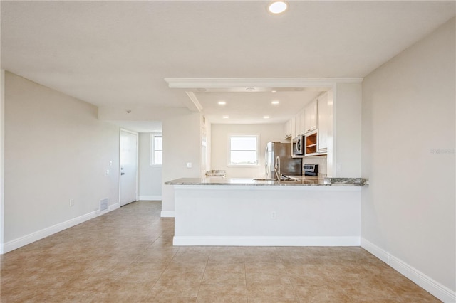 kitchen with white cabinetry, appliances with stainless steel finishes, light stone counters, and kitchen peninsula