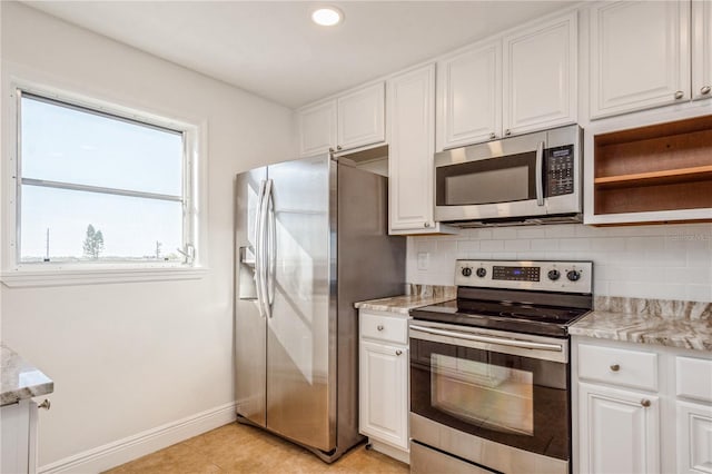 kitchen featuring light stone counters, backsplash, white cabinets, and appliances with stainless steel finishes