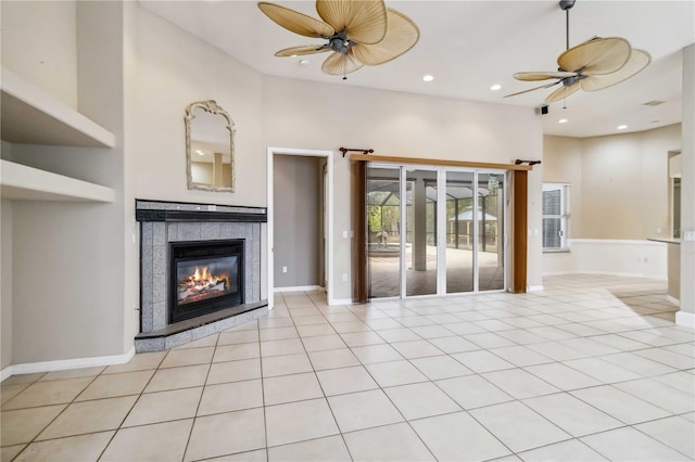 unfurnished living room featuring a tiled fireplace, light tile patterned flooring, and ceiling fan