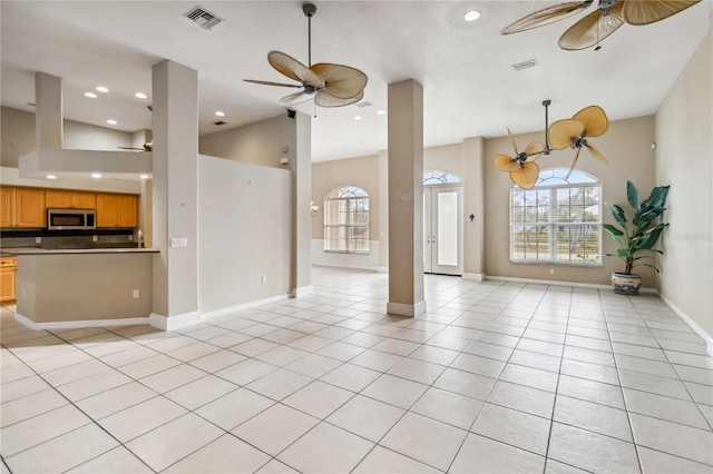 unfurnished living room with a healthy amount of sunlight, light tile patterned floors, and ceiling fan