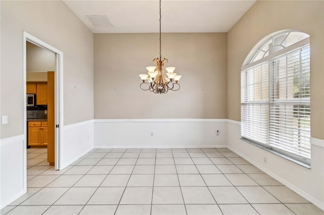 tiled spare room with a chandelier