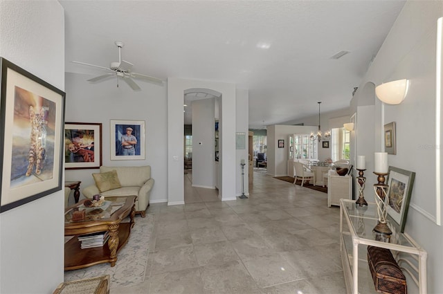 living room featuring vaulted ceiling and ceiling fan with notable chandelier