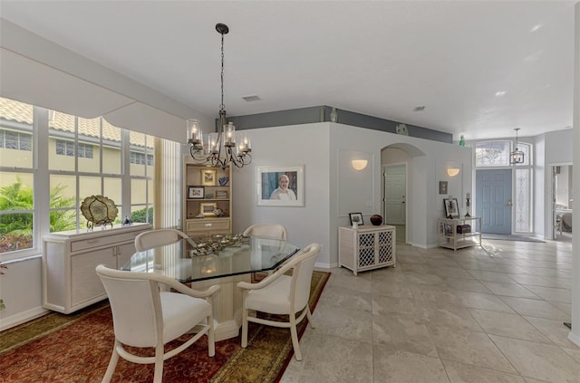 tiled dining area featuring a notable chandelier and a wealth of natural light