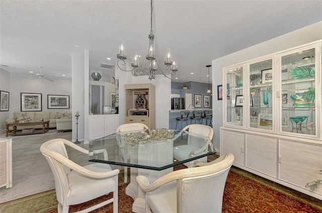 dining area featuring ceiling fan with notable chandelier and a textured ceiling