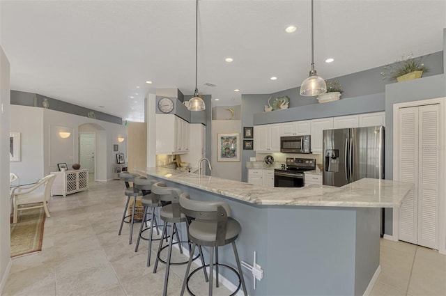 kitchen with hanging light fixtures, white cabinets, kitchen peninsula, and stainless steel appliances