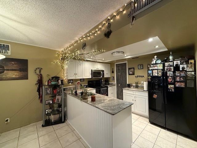 kitchen featuring black refrigerator with ice dispenser, white cabinetry, range, and kitchen peninsula