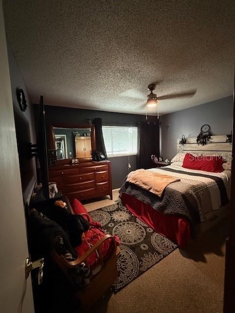 bedroom with ceiling fan, a textured ceiling, and carpet flooring