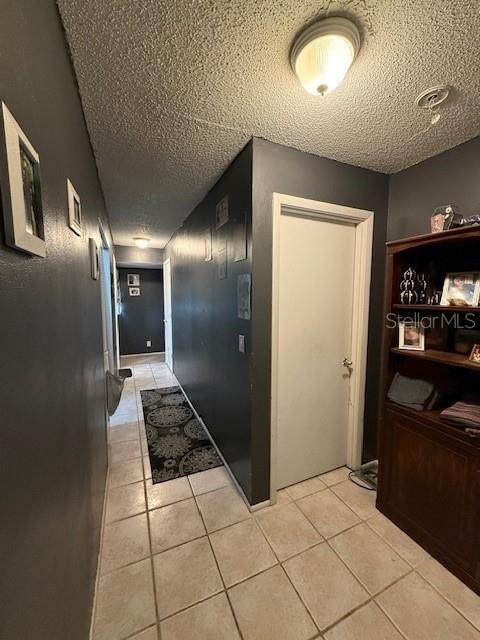 hallway featuring a textured ceiling and light tile patterned flooring