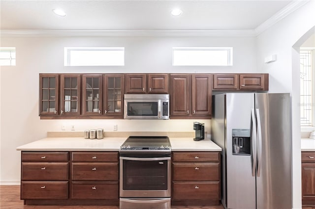 kitchen featuring crown molding, dark brown cabinetry, stainless steel appliances, and hardwood / wood-style flooring