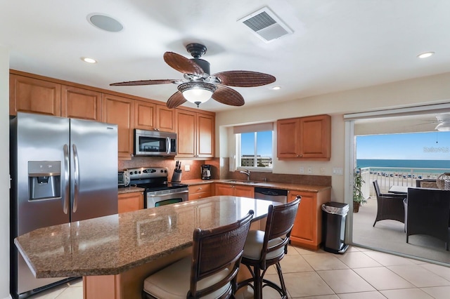 kitchen featuring a center island, visible vents, appliances with stainless steel finishes, a sink, and a kitchen bar