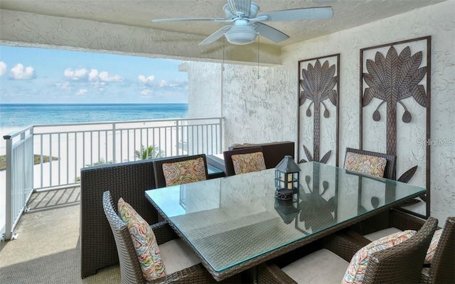 sunroom / solarium featuring a water view, ceiling fan, and a beach view