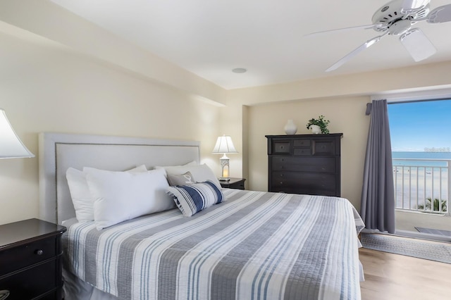 bedroom with a ceiling fan, a water view, and wood finished floors