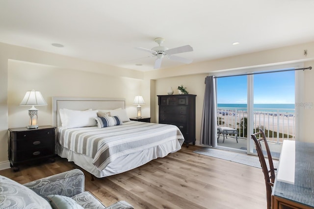 bedroom with access to exterior, a water view, ceiling fan, and wood finished floors