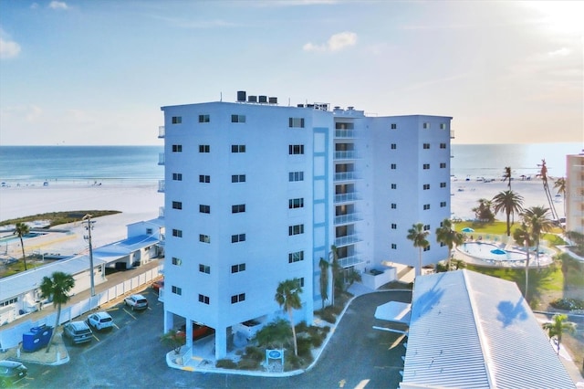 view of building exterior featuring a water view and a beach view