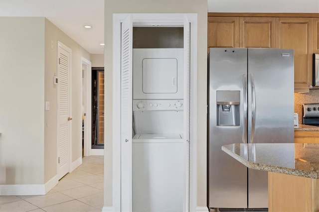 washroom with light tile patterned floors, recessed lighting, laundry area, stacked washer / dryer, and baseboards