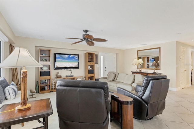 living area featuring light tile patterned flooring, a ceiling fan, and baseboards