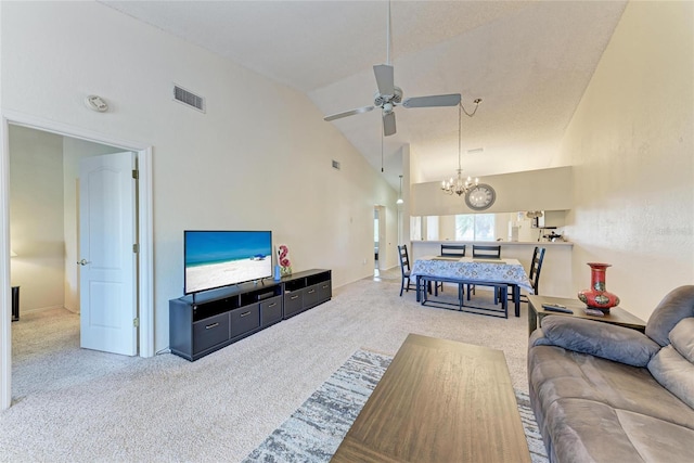 carpeted living room featuring ceiling fan with notable chandelier and high vaulted ceiling