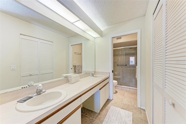 bathroom with tile patterned flooring, vanity, a textured ceiling, toilet, and walk in shower