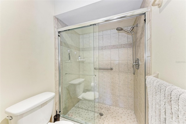 bathroom featuring a shower with door and toilet