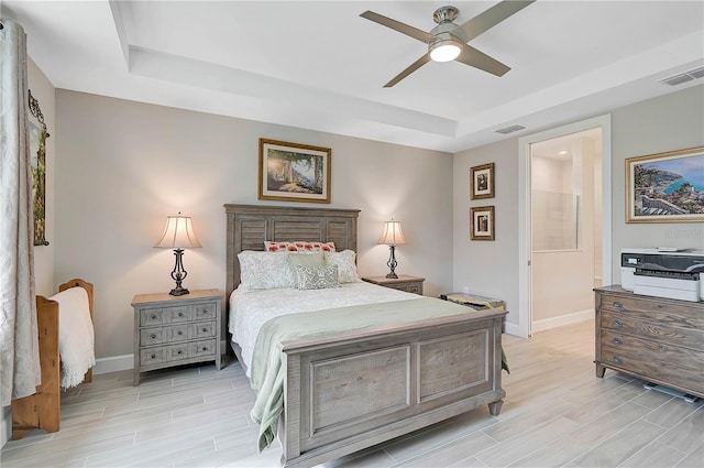 bedroom with ceiling fan, light hardwood / wood-style floors, and a raised ceiling