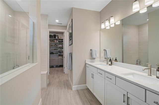 bathroom featuring tiled shower and vanity