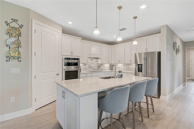 kitchen with appliances with stainless steel finishes, white cabinetry, a center island with sink, and sink