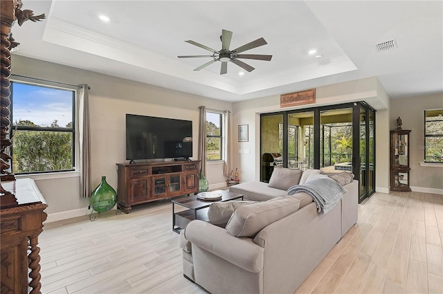 living room with a raised ceiling, ceiling fan, and light hardwood / wood-style floors