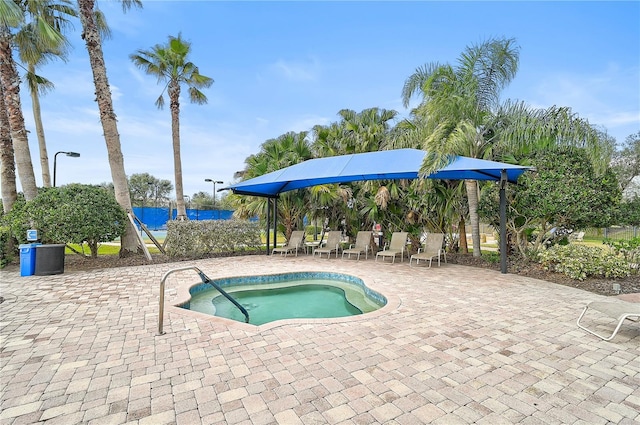 view of swimming pool featuring a water view, a patio area, and an in ground hot tub