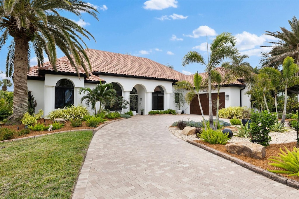 mediterranean / spanish house featuring a garage and a front lawn