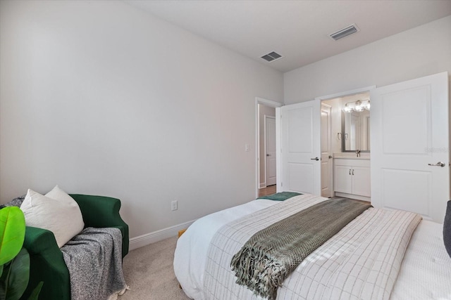 bedroom featuring ensuite bathroom and light colored carpet