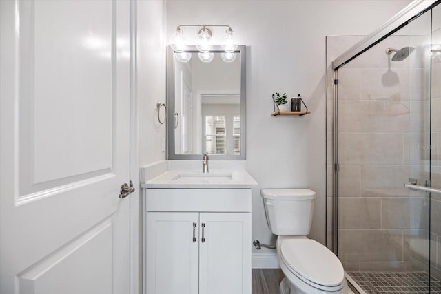 bathroom featuring toilet, vanity, and a shower with door