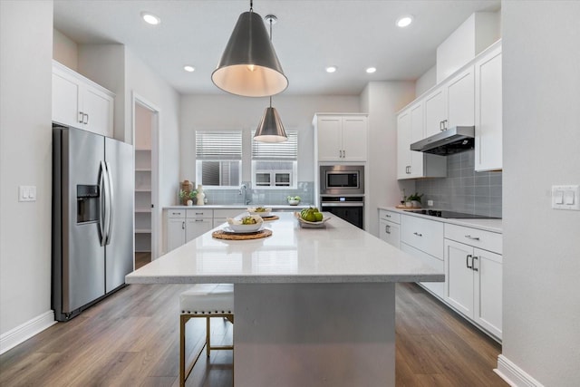 kitchen with a center island, white cabinetry, wood-type flooring, stainless steel appliances, and hanging light fixtures