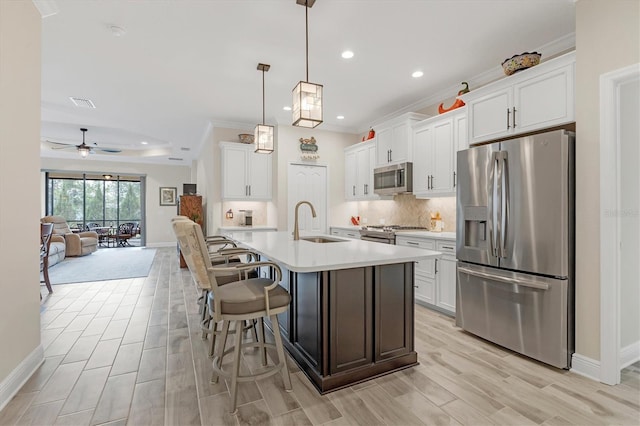 kitchen with a center island with sink, white cabinetry, stainless steel appliances, and pendant lighting