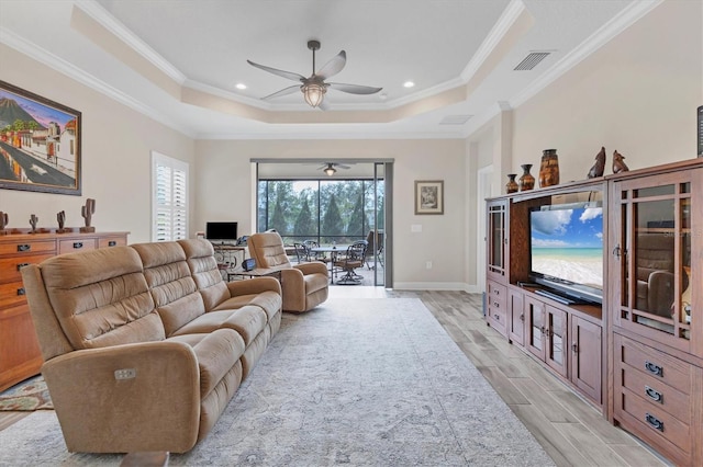 living room featuring ceiling fan, a tray ceiling, and crown molding