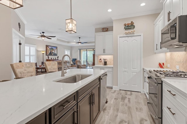 kitchen featuring stainless steel appliances, backsplash, decorative light fixtures, and sink