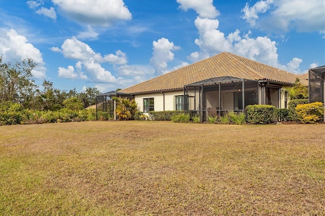 rear view of house featuring a yard and glass enclosure