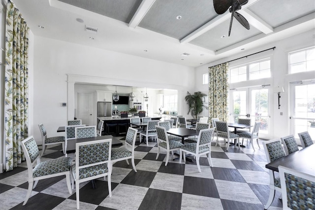 dining room with coffered ceiling, ceiling fan, beam ceiling, and a high ceiling